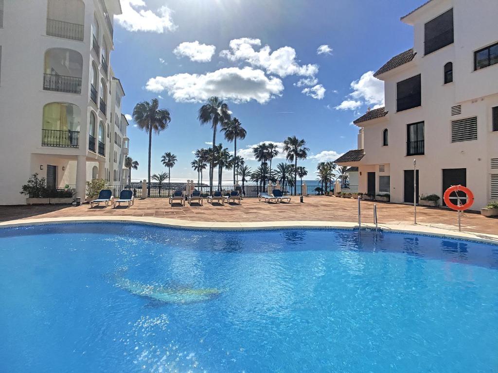 a large blue swimming pool next to two buildings at Duquesa Superb Seafront Apartment Marina Real in Manilva