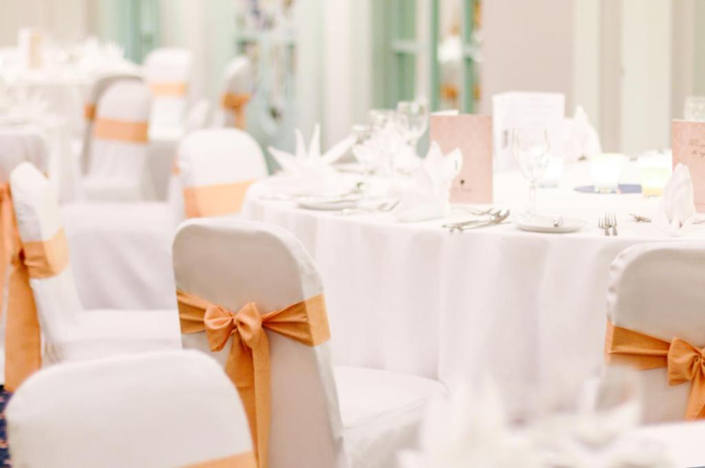 a row of tables with white chairs with orange bows at AX The Victoria Hotel in Sliema