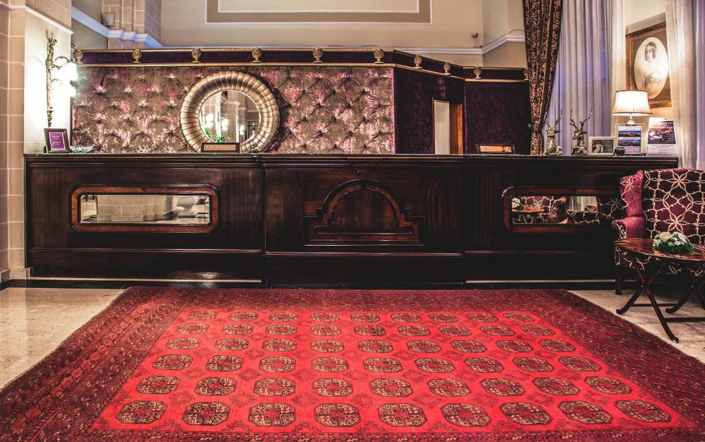 a living room with a red rug and a mirror at AX The Victoria Hotel in Sliema