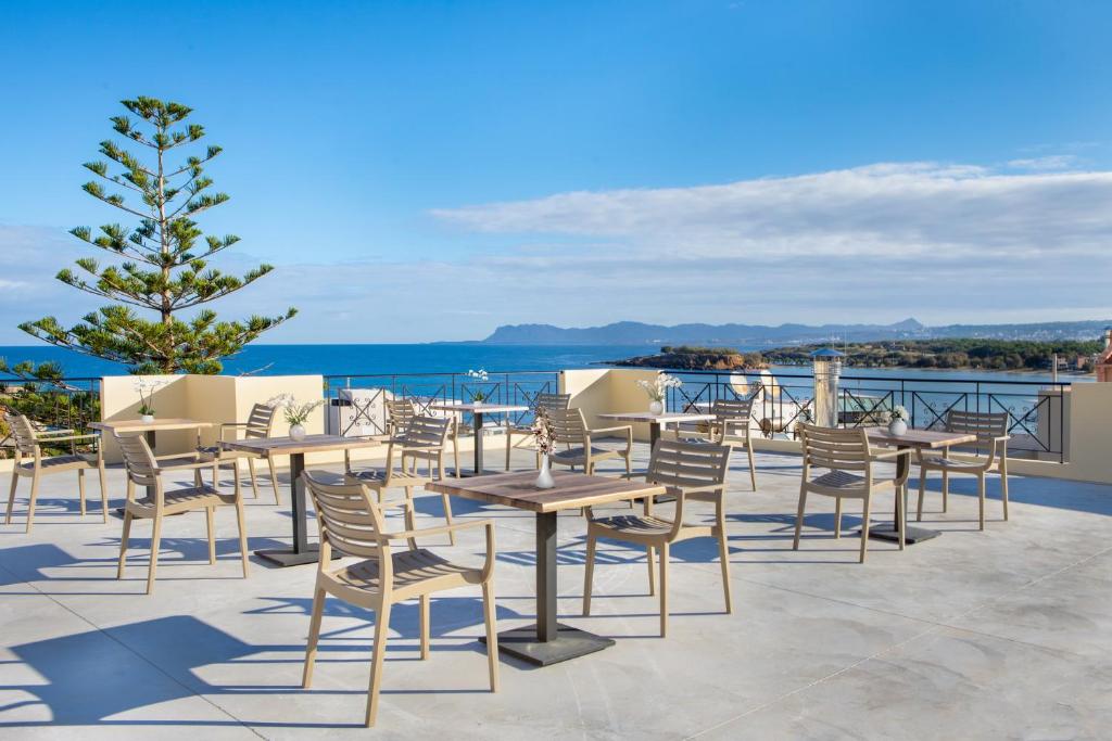 un patio con tavoli, sedie e vista sull'oceano di Evi Boutique Rooms a Galatás