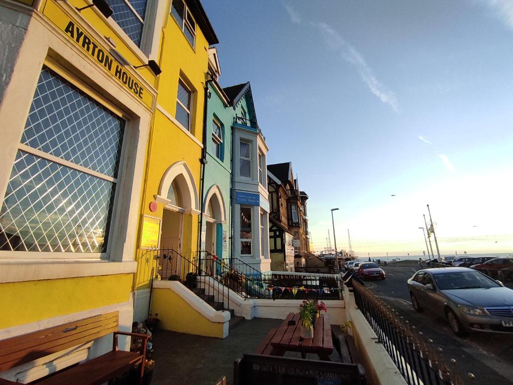 un edificio amarillo con un coche estacionado al lado de una calle en Ayrton House Holiday Apartments, en Blackpool