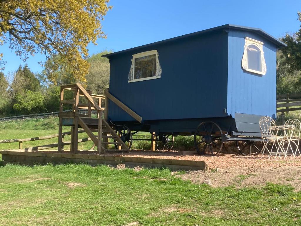 a blue tiny house sitting on a wooden platform at Original Roadsmans Wagon with breathtaking views in Longhope