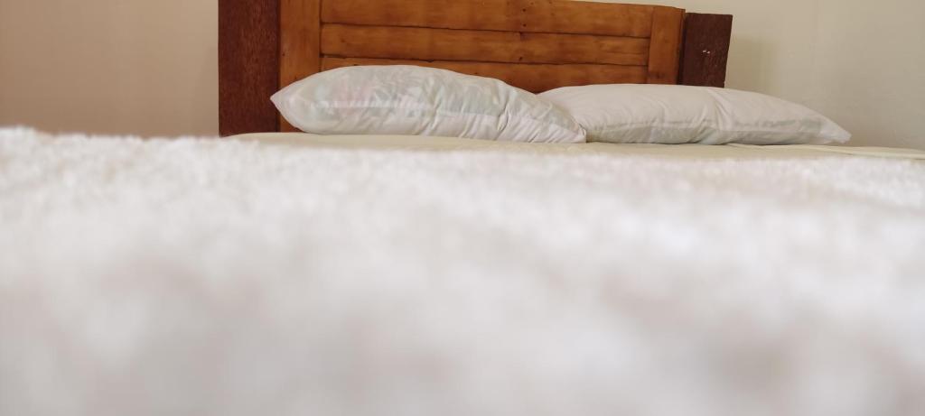 uma cama com lençóis brancos e duas almofadas em rancho durian hotel y restaurante em Las Galeras
