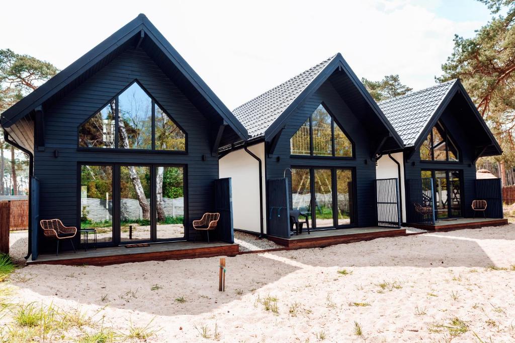 Casa en blanco y negro con ventanas grandes en Domki na wydmie, en Dziwnówek