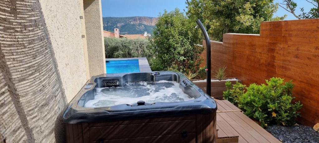 una bañera de hidromasaje en una terraza junto a una valla en Rêves de vie, appartement vue mer, grande piscine privée , spa privatif, en Cassis