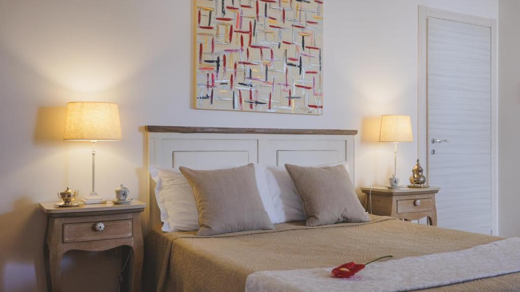 een slaapkamer met een bed met 2 lampen en een schilderij bij MaNanna B&B in Marzamemi