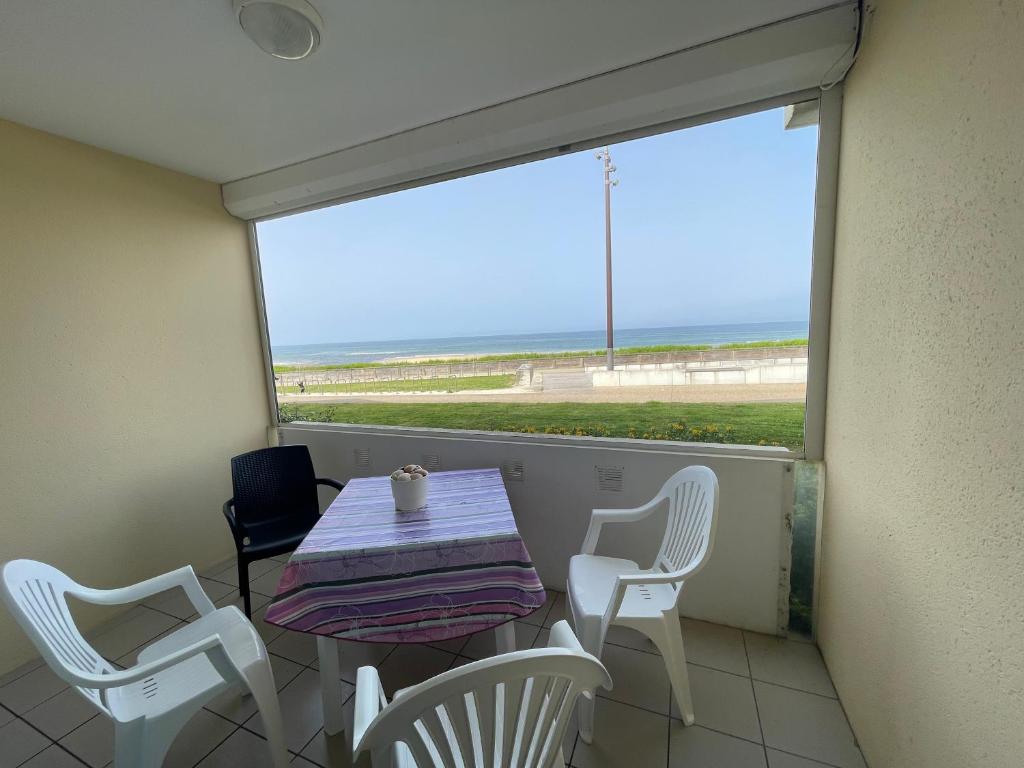 une table et des chaises sur un balcon avec vue sur la plage dans l'établissement Le Bruit Des Vagues, à Mimizan