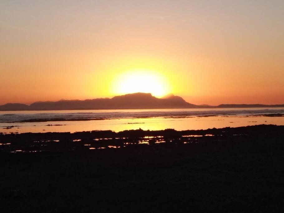 a sunset over the ocean with a mountain in the background at Sunset Paradise in Cape Town