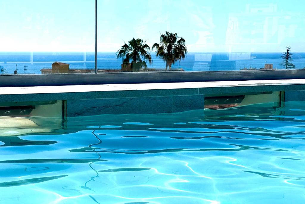 una piscina con agua azul y palmeras en Hotel Sireno Torremolinos - Adults Only, Ritual Friendly, en Torremolinos