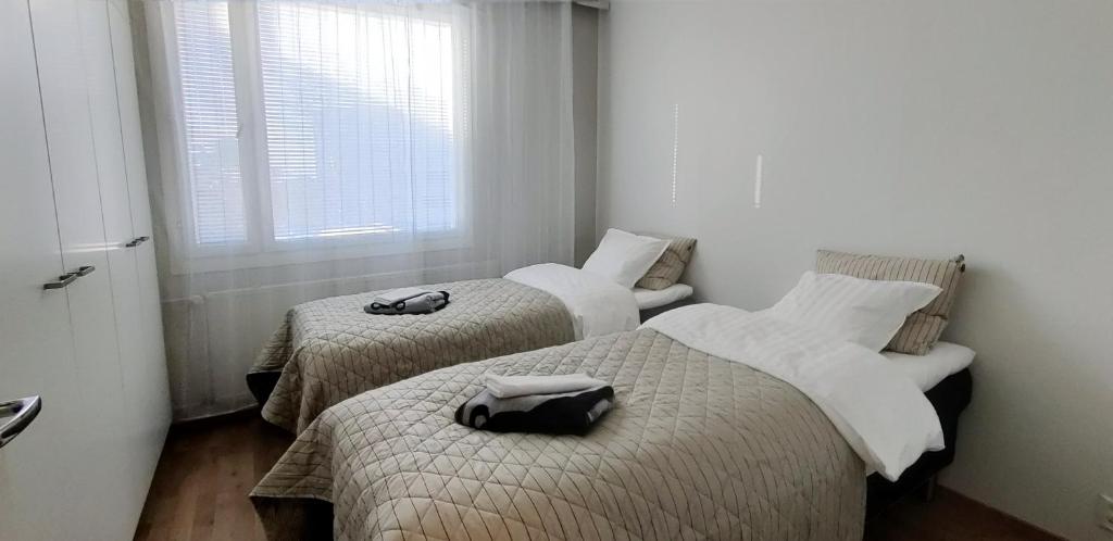 two beds in a small room with a window at Niinivaara apartment saunallinen ja ilmastoitu majoitus in Joensuu
