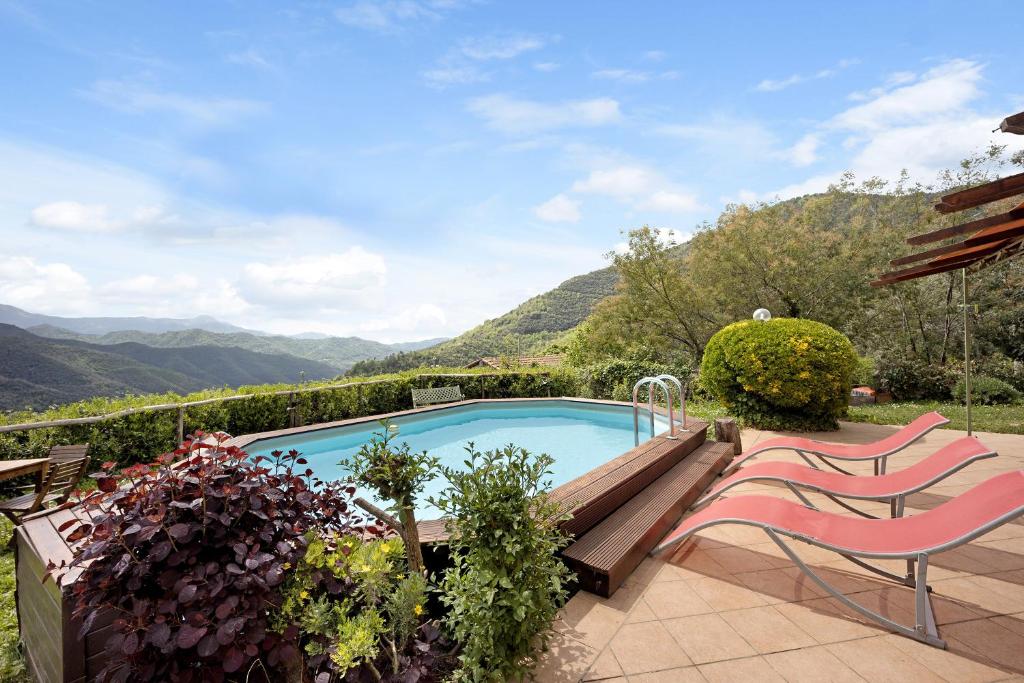 a swimming pool in a garden with two chairs at Villa La Casa di Giacomo in Pigna