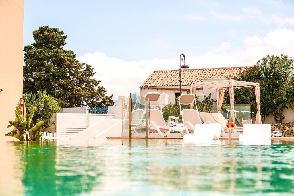 a pool of water with chairs and a gazebo at Hotel Baglio Di Scopello in Scopello