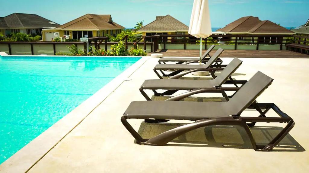 a group of lounge chairs next to a swimming pool at Villas Richmond Estate - Ocho Rios in Richmond