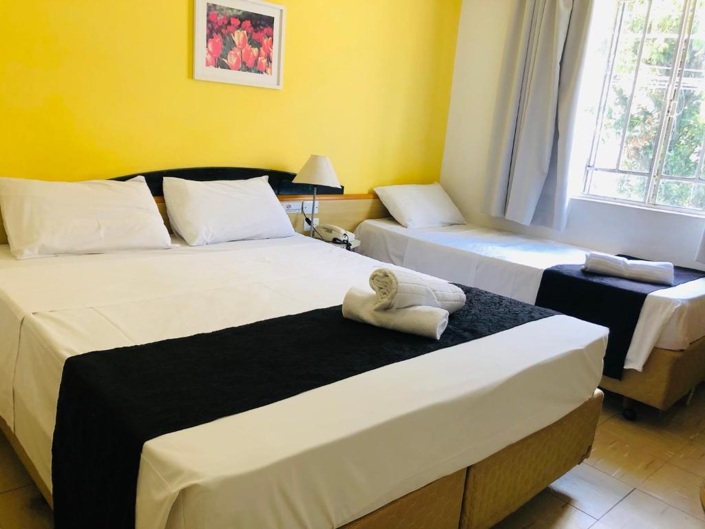 a bedroom with two beds with towels on them at Hotel Blumenau Centro in Curitiba