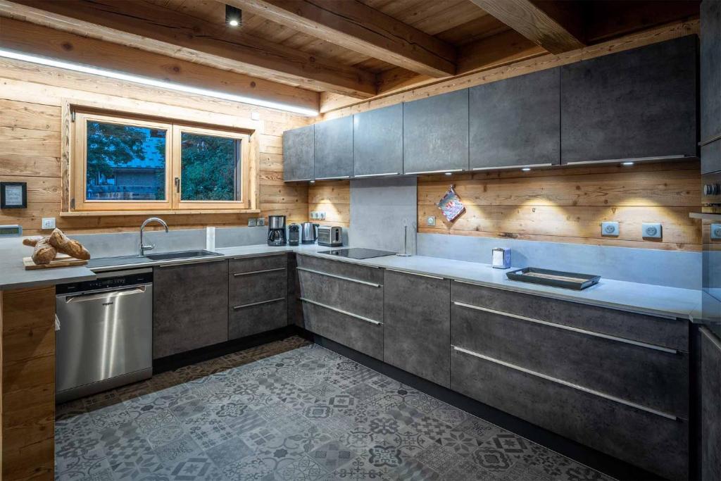 a kitchen with stainless steel appliances and wooden walls at Madame Vacances Chalet Woodpecker in L'Alpe-d'Huez