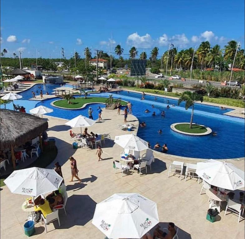 ein großer Pool mit Menschen in einem Resort in der Unterkunft Muro Alto Condomínio Clube - FLAT TÉRREO in Porto De Galinhas