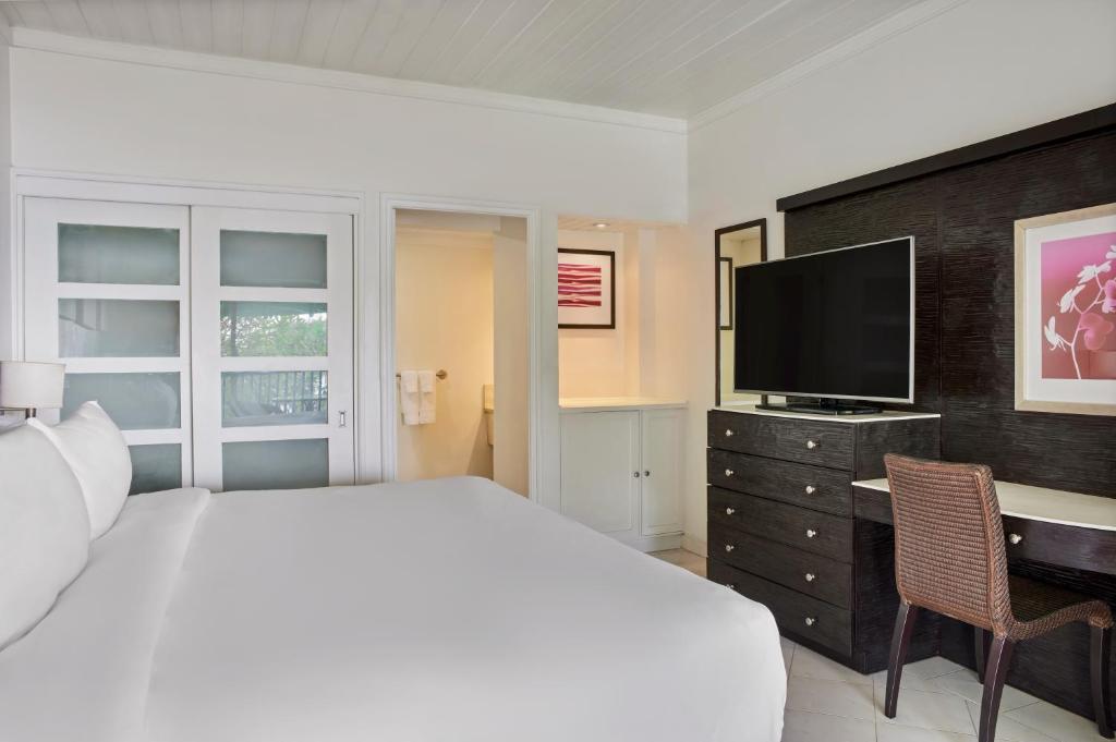 a bedroom with a bed and a desk with a television at Crystal Cove, Barbados, A Tribute Portfolio All-Inclusive Resort in Saint James