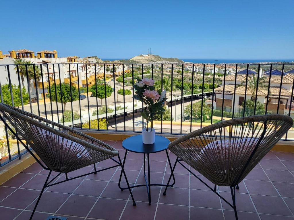 un balcón con 2 sillas y una mesa con un jarrón de flores en ¡Precioso apartamento con fantásticas vistas en Al-Andalus Thalassa!, en Vera