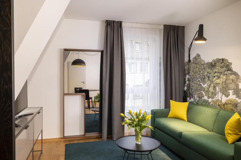 a living room with a green couch and a mirror at Hôtel Du Dragon in Strasbourg