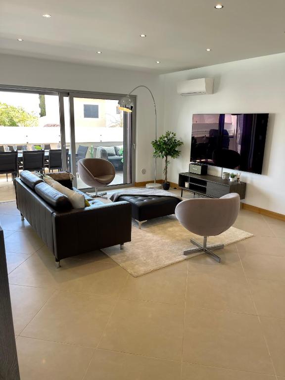 a living room with a black leather couch and chairs at Beach condo Porto mós (sea view) in Lagos