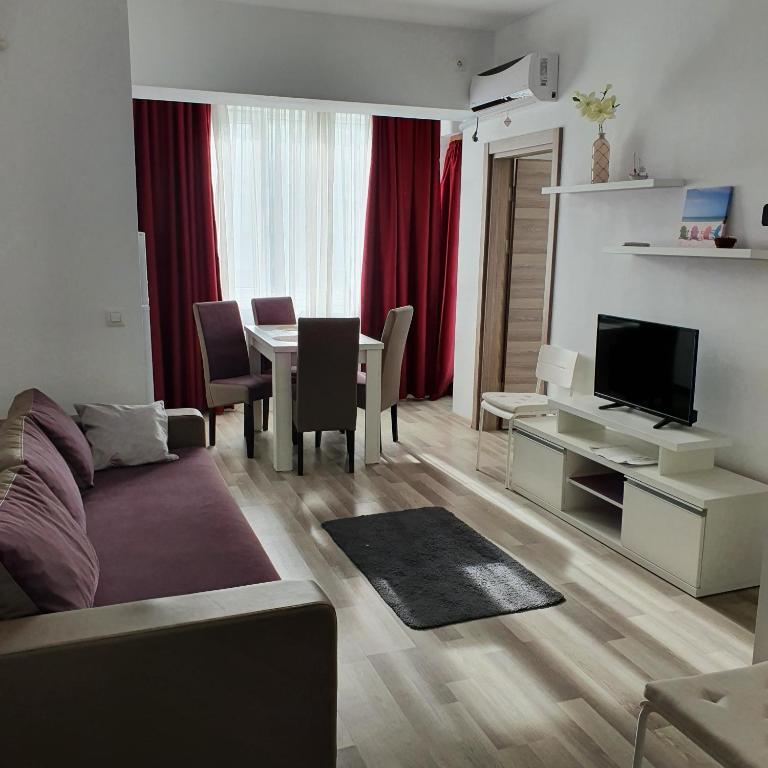 un soggiorno con divano e tavolo con TV di Summerland Apartament a Mamaia