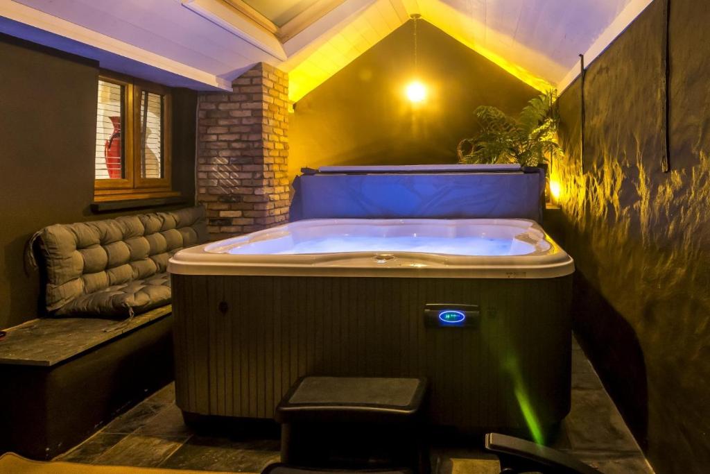 a jacuzzi tub in a room with a couch at Foxglove - Luxurious Barn Conversion - Blossom Farm in Johnston