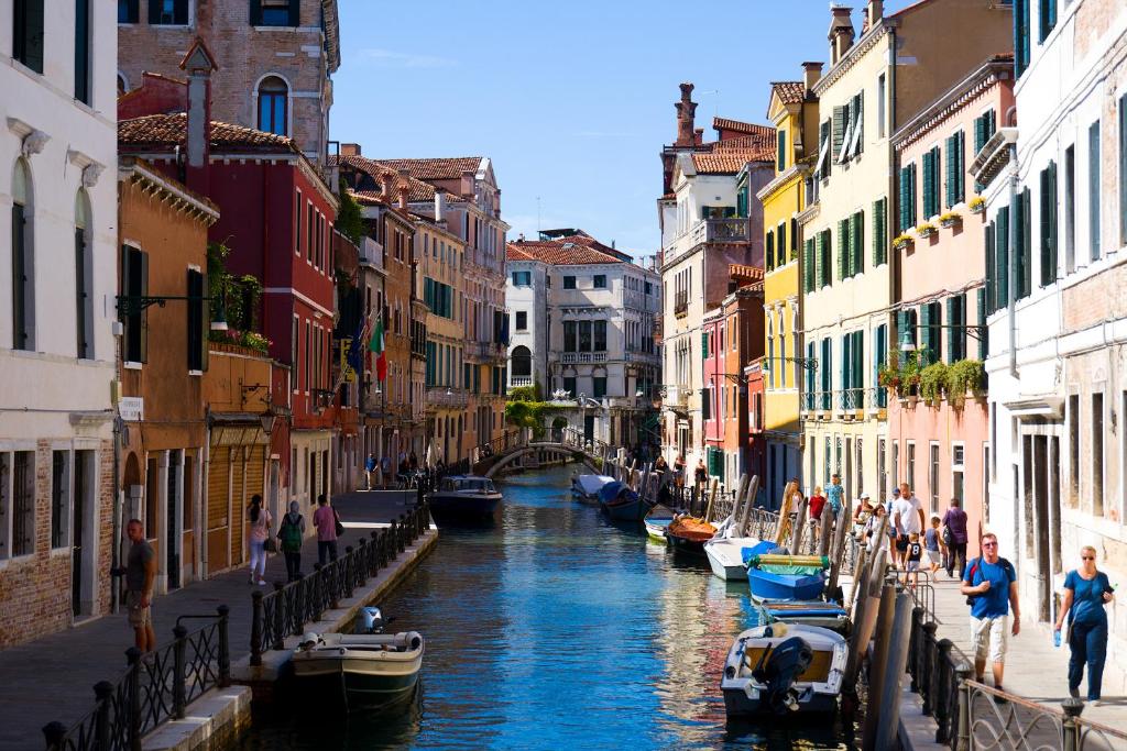 a group of people walking along a canal with boats at New Campsite in Camping Ca' Savio in Cavallino-Treporti