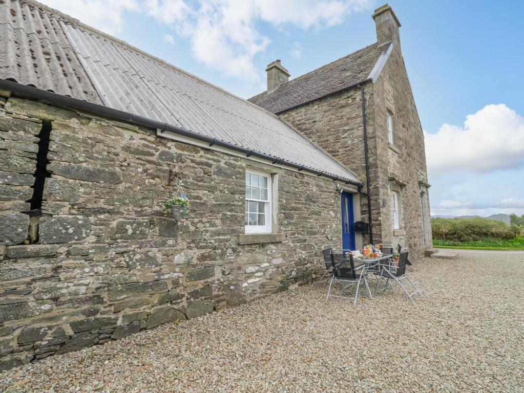 an old stone house with a table in front of it at Seaview-Barsloisnach Cottage in Kilmartin