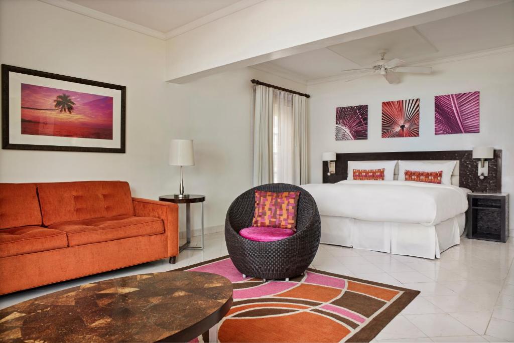a bedroom with a bed and a couch and a table at Crystal Cove, Barbados, A Tribute Portfolio All-Inclusive Resort in Saint James