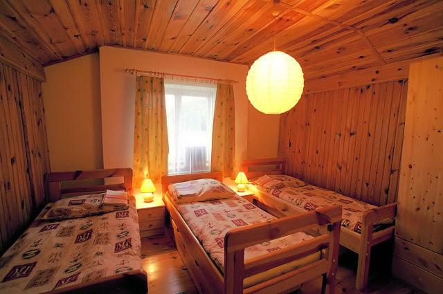 a bedroom with two beds and a window and a chandelier at Gospodarstwo Agroturystyczne U Zdzicha in Bałtów