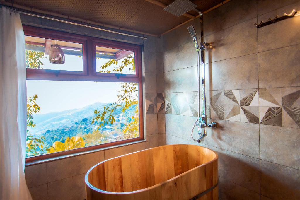 ein Bad mit einer Holzbadewanne und einem Fenster in der Unterkunft Không gian văn hóa trà Suối Giàng in Văn Chấn