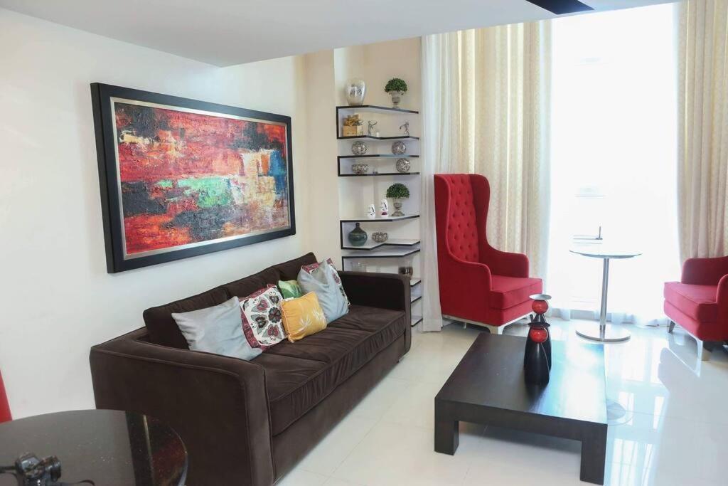 a living room with a brown couch and a red chair at Huge Loft Type Condo At Queen City of the South in Cebu City