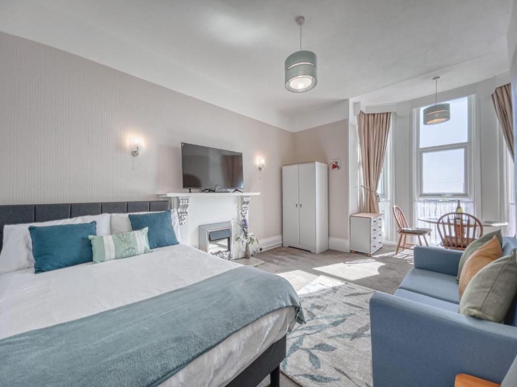 a bedroom with a bed and a couch and a television at Apartment 1 Large Studio Sea Front- Sea Views- Free Parking in Paignton