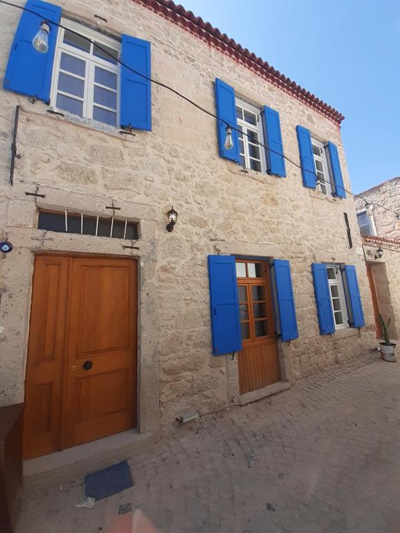 a stone building with blue shutters on it at Merlara Otel Alaçatı in Alaçatı