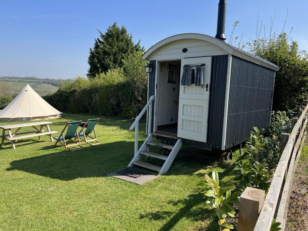 um pequeno barracão com uma mesa e uma tenda em Home Farm Shepherds Hut with Firepit and Wood Burning Stove em High Wycombe