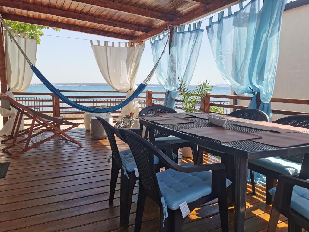 uma sala de jantar com uma rede de descanso, uma mesa e cadeiras em Adriatik Escape em Privlaka