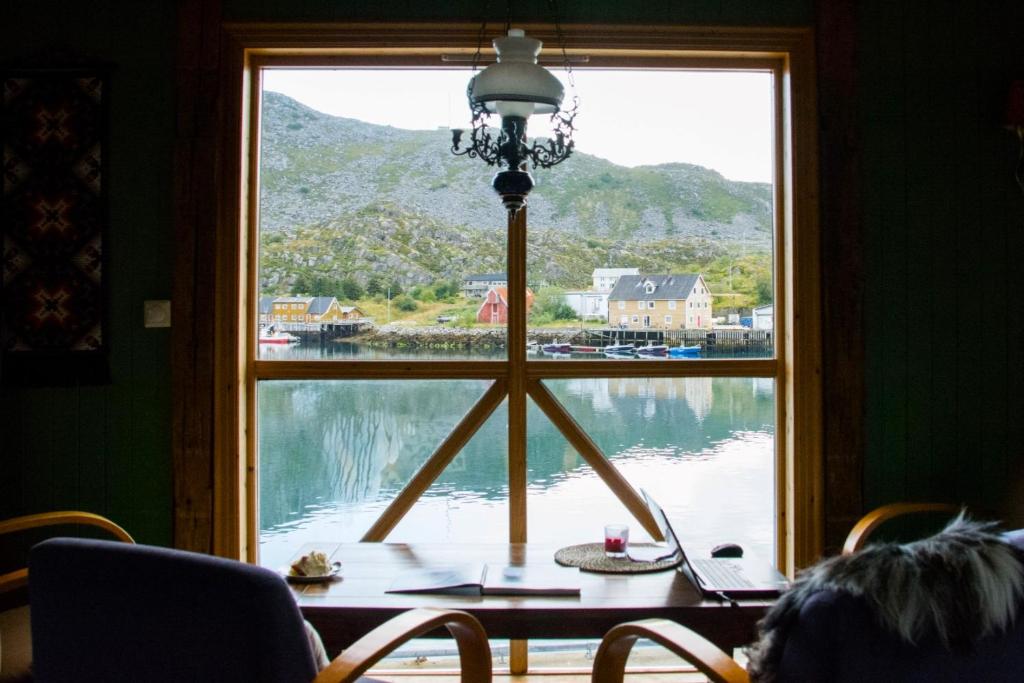 a window with a table and a view of a lake at Heimbrygga Restaurant & Accommodation in Skrova