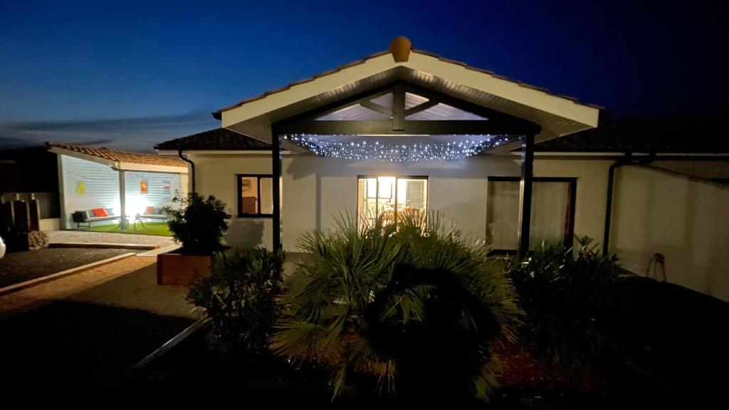 a house with a lit up gazebo with lights at Villa moderne avec spa à Montalivet in Vensac