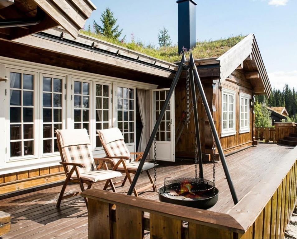 特呂西爾的住宿－ReveEnka - cabin in Trysil with Jacuzzi for rent，一个带两把椅子和火坑的甲板