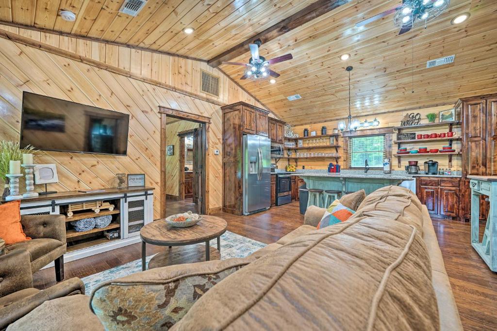 a living room with a couch and a kitchen at Setting Sun Cabin with Private River Access in Eagletown