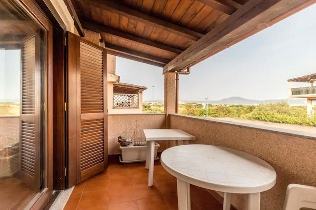 einen Balkon mit einem weißen Tisch und einem Fenster in der Unterkunft 2 bedrooms apartement with sea view furnished terrace and wifi at Olbia 5 km away from the beach in Olbia