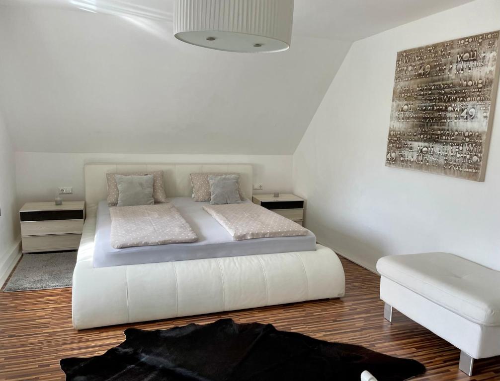 um quarto com uma cama branca e uma cadeira branca em Ferienwohnung H&H Happy Holiday em Velden am Wörthersee