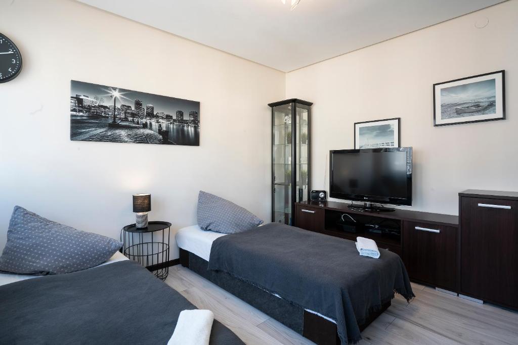 Cette chambre comprend 2 lits et une télévision à écran plat. dans l'établissement 02 Gdynia Centrum - Apartament Mieszkanie dla 2 os, à Gdynia