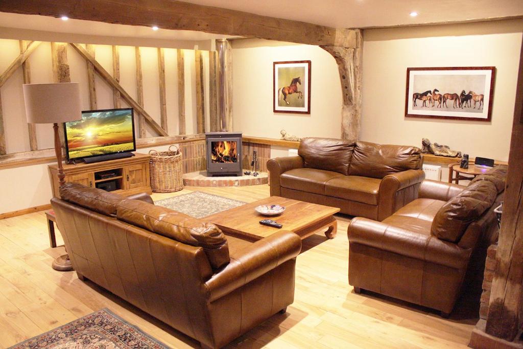 a living room with leather furniture and a fireplace at The Coach House Barn - Valley Farm in Sudbourne