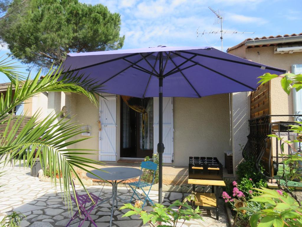 un ombrellone viola e un tavolo con sedie su un patio di Au coeur de la Provence Verte a Le Cannet-des-Maures