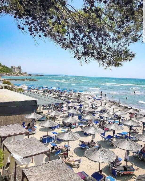 a beach with many chairs and umbrellas and the ocean at Marconi Apartments in Durrës