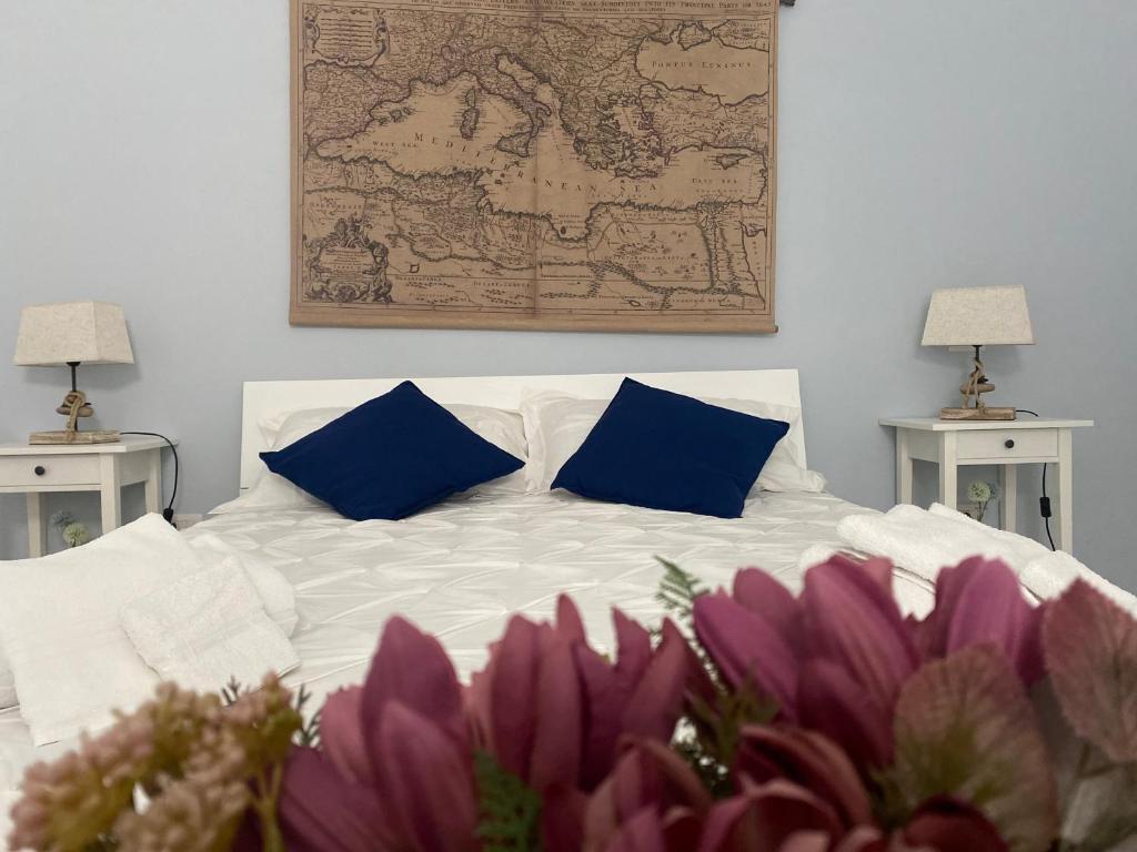 un letto bianco con 2 cuscini blu e una mappa sul muro di Lemonsea amalfitan house a Vietri