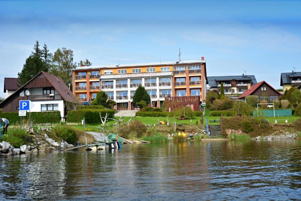 a building next to a river with people on the shore at Pension Calla in Dolní Vltavice