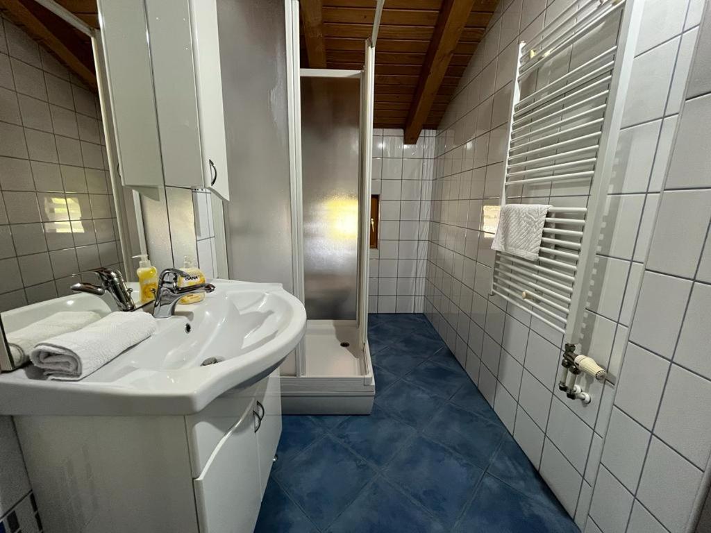 a white bathroom with a sink and a shower at Apartmani M&D in Laktaši