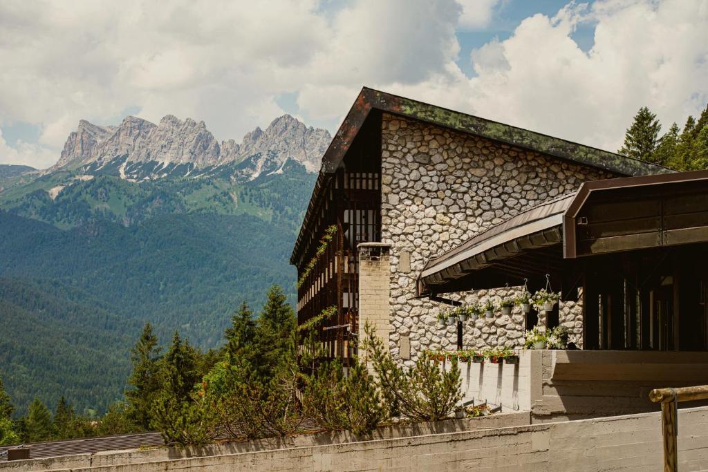 um edifício de pedra com montanhas ao fundo em Hotel Boite em Borca di Cadore